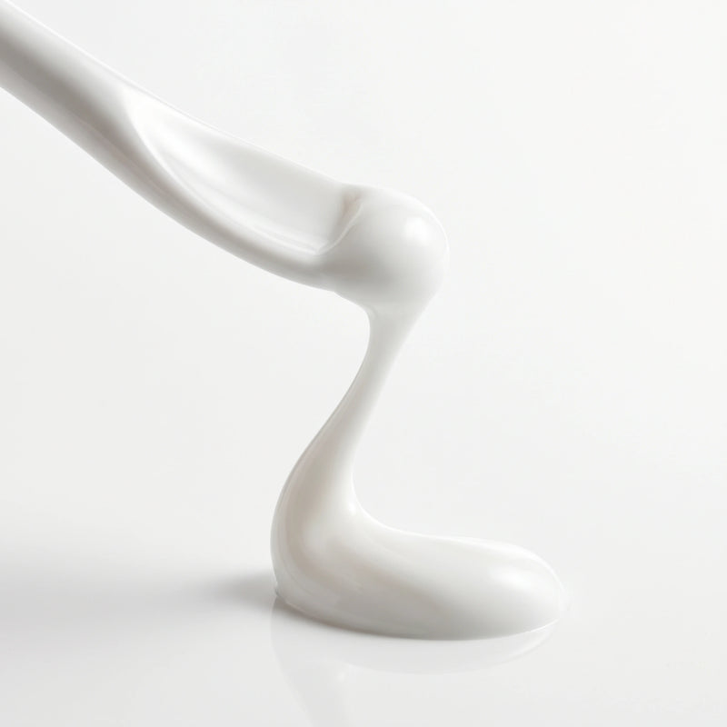 Macro close-up of smooth, white BOTANĒ skincare cream dripping onto a glossy white surface. product image