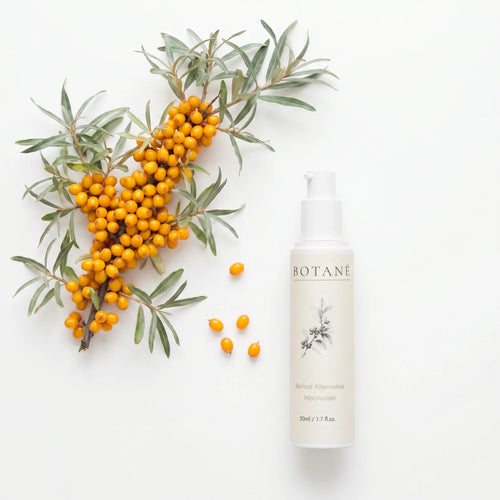 A flat lay photograph on a white background showing a 50ml bottle of BOTANĒ Retinol Alternative Moisturiser next to a fresh sea buckthorn branch with vibrant orange berries.
