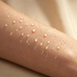 Close-up of glowing, hydrated skin covered in clear water droplets in warm light, representing BOTANĒ skincare moisture. thumbnail 5