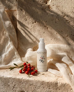 BOTANĒ Retinol Alternative Serum pump bottle on textured stone with red rosehips and draped linen in bright sunlight. thumbnail 1